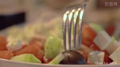 特写镜头从新鲜的<strong>希腊</strong>沙拉中取出黑橄榄健康的素食